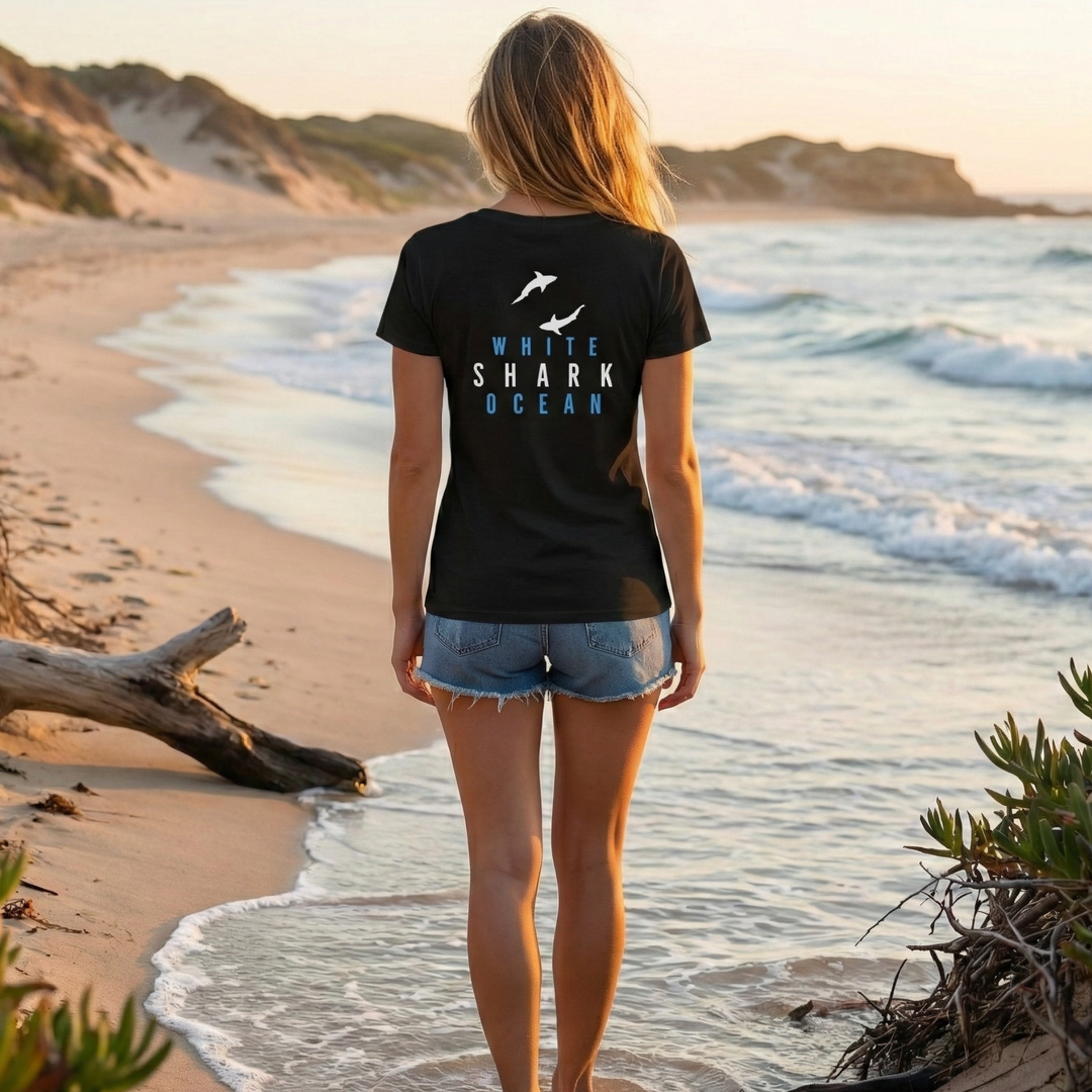 Beach lifestyle scene with woman in black t-shirt walking along shoreline at sunset