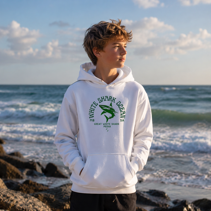 Person wearing a white hoodie with a shark design on a beach
