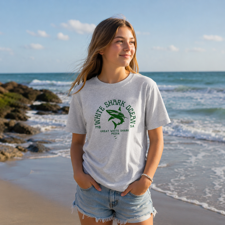 Person wearing a grey t-shirt with a shark graphic on a beach white shark ocean media